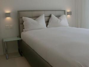 苏黎世VISIONAPARTMENTS Binzmühlestrasse 46 - contactless check-in的一张带枕头和床头柜的大型白色床