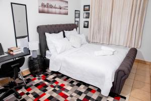 卢萨卡Retreat Aparthotel-Garden-Solar-Wi-Fi -Firepit-Park-carport的一间卧室配有一张带白色床单的床和一张书桌。