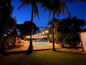 巴西利亚Casa do Lago Hospedaria的棕榈树和灯光的夜间游泳池