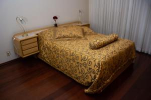普拉杜斯Apart Hotel Água Limpa的一间卧室配有一张床和一个带灯的床头柜