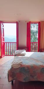 萨兰托Hotel Natura Cocora的一间卧室设有一张床和两个大窗户