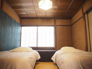松江市Guest House SUETUGU的带窗户的客房内的两张床