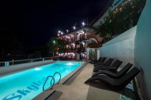 科隆天空度假酒店的一座游泳池,在晚上在大楼旁边摆放着椅子