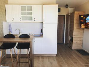 迪瓦伊巴雷Apartman Ambijent Divcibare的厨房配有白色橱柜和木桌