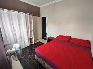 雅温得Residence Jardin Tropical的卧室配有红色的床和风扇
