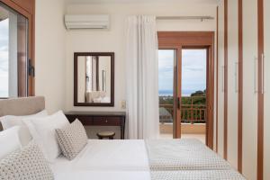 特里欧皮特拉Triopetra Luxury Villas Panagia的一间带白色床的卧室和一个阳台