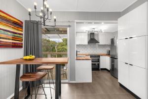 赫本温泉Locarno Cottage的厨房配有白色橱柜和木桌