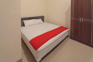 WeversdorpRedDoorz Syariah near Sentani City Square的一间卧室配有一张带红色毯子的床