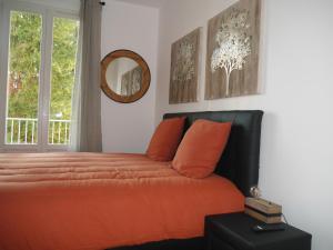 奥赛Spacieux F5 au parc arboré的一间卧室配有带橙色枕头和镜子的床