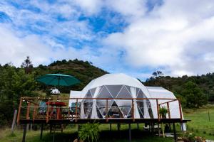 瓜塔维塔Glamping Claro de Luna的甲板上带遮阳伞的大型圆顶帐篷