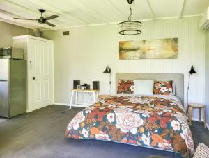 赫本温泉Aurora Cottage的一间卧室配有一张带花卉床罩的床和一台冰箱