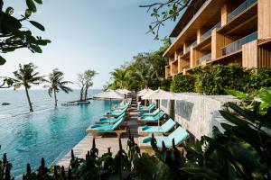 北芭堤雅Cape Dara Resort - SHA Plus的度假酒店的游泳池配有躺椅和遮阳伞