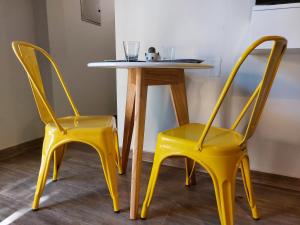 查克拉斯德科里亚Moderno departamento para dos personas en Chacras de Coria的两张黄色椅子,旁边是一张桌子,桌子上是黄色桌子