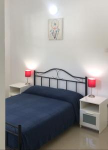 努格古达宾至如归度假屋的一间卧室配有一张蓝色的床和两张带台灯的桌子。