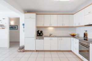 埃雷特里亚Beachfront Modern Apartment的厨房配有白色橱柜和白色瓷砖地板。