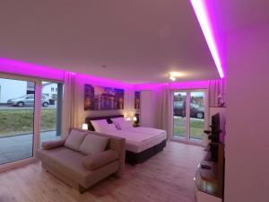 富尔达-Neubau- 68 qm 2-Zimmer-Wohnung的一间卧室配有一张床、一张沙发和粉红色的灯光