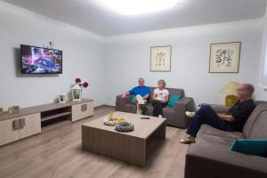 奥查加维亚安纳姆蒂农家酒店的三人坐在客厅看电视