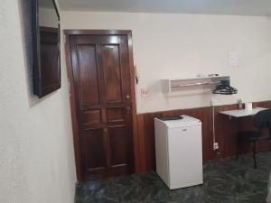 巴西利亚Pousada do Luquinhas的厨房设有木门和小冰箱