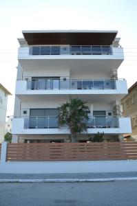 帕拉利亚卡泰里尼斯Aqua Mare Luxury Apartments的一座白色的建筑,前面有棕榈树