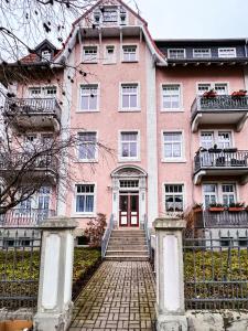 爱尔福特Apartment am Landtag的粉红色的建筑,前面有楼梯