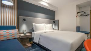 青岛青岛中心智选假日酒店(五四广场&奥帆中心)的卧室配有白色的床和蓝色椅子