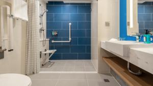 青岛青岛中心智选假日酒店(五四广场&奥帆中心)的浴室铺有蓝色瓷砖,设有盥洗盆和卫生间。