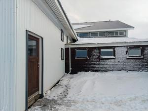 ÞórshöfnGrásteinn Guesthouse的雪中有一扇门的白色建筑
