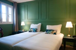 巴黎Hôtel Petit Saint-Honoré的绿化客房的两张床,配有两盏灯