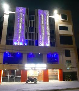 加尔各答金色天堂酒店的停在一座紫色灯的建筑前面的摩托车