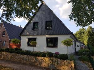 特森Ferienwohnung-Haus Holly的白色的房子,设有黑窗和石墙