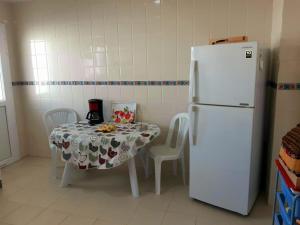 迦玛特Perle de Gammarth的厨房配有桌子和白色冰箱。