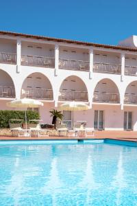 巴哈撒丁岛Club Hotel Cormorano的酒店前的游泳池配有椅子和遮阳伞