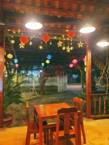 Quan TomCat Tien Farmer Lodge的木桌和椅子,天花板上挂着遮阳伞