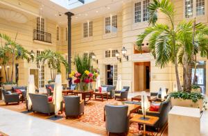 华沙波洛尼亚宫大酒店的大堂设有桌椅和棕榈树