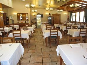 Olave罗伦托旅馆的用餐室配有白色的桌子和木椅