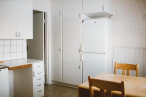 ÅseleLappland Pro Natur的厨房配有白色橱柜、桌子和冰箱。