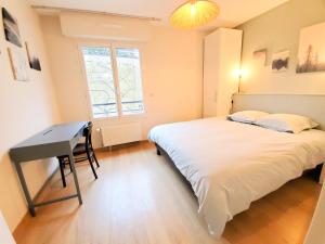 拉瓦勒Standing appartement avec vue sur la Mayenne的一间卧室配有一张床、一张书桌和一个窗户。