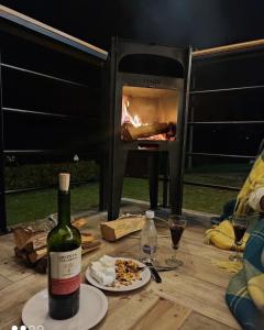 ChiquinquiráAcogedor y moderno Glamping en container, 10 min del centro的餐桌上摆放着一瓶葡萄酒,配以比萨饼和烤箱