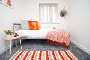 纽波特Dock House - 5 Bedroom House - Sleeps 7的白色的客房配有带橙色枕头和桌子的床
