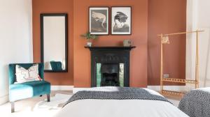 纽波特Tŷ Hapus Newport - Luxury 4 Bedroom Home的一间卧室设有橙色的墙壁和壁炉