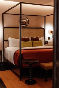 圣米格尔-德阿连德Casa Hoyos - Hotel Boutique的一间卧室配有一张四柱床和凳子