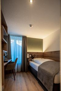 NiederbippHotel & Restaurant Bären的一间卧室配有一张床、一张书桌和一个窗户。