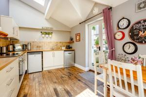 切普斯托Broadrock Accommodation - Clock Cottage的厨房铺有木地板,配有白色橱柜。