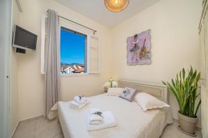 阿尔戈斯托利翁Flowers in the city - Elegant Home in Argostoli的一间卧室配有带毛巾的床和窗户。