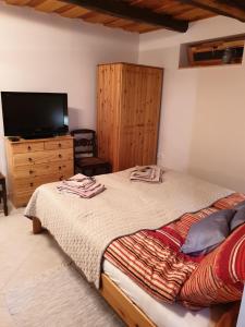 佐洛恰尼Kis Ház Apartman的一间卧室配有一张床和一个带电视的梳妆台