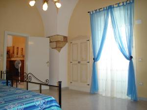 Montesano SalentinoLa Corte Antica的一间卧室配有床和蓝色窗帘的窗户