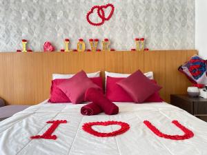 吉隆坡Private Jacuzzi Staycation at KL City 152的一张带红色枕头的床,上面写着爱情