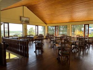 努沃勒埃利耶茶布什酒店的用餐室设有桌椅和窗户。