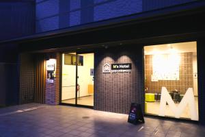 京都M's Hotel Gojo Odawara的窗口上带有m符号的商店前方