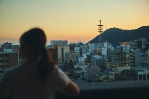 高松FAV HOTEL TAKAMATSU的日落时分看着城市的女人